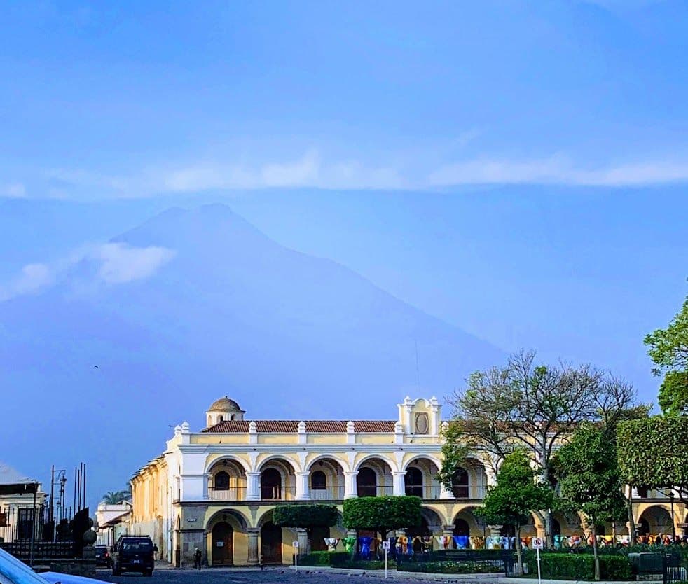 The yellow arcaded Palacio del Ayuntamiento on Parque Central with Volcán de Agua behind it