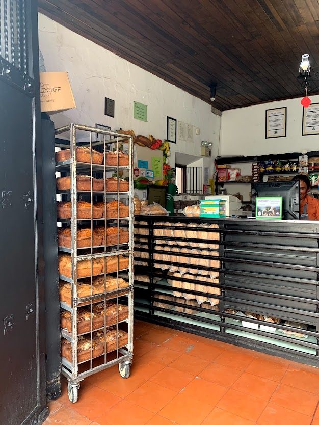 Loaves of bread on a metal rack beside the bread counter, over a tiled floor