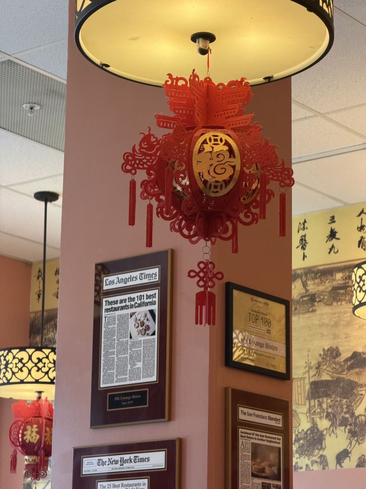 Red paper lantern and framed press clippings on a salmon-colored pillar at HK Lounge Bistro