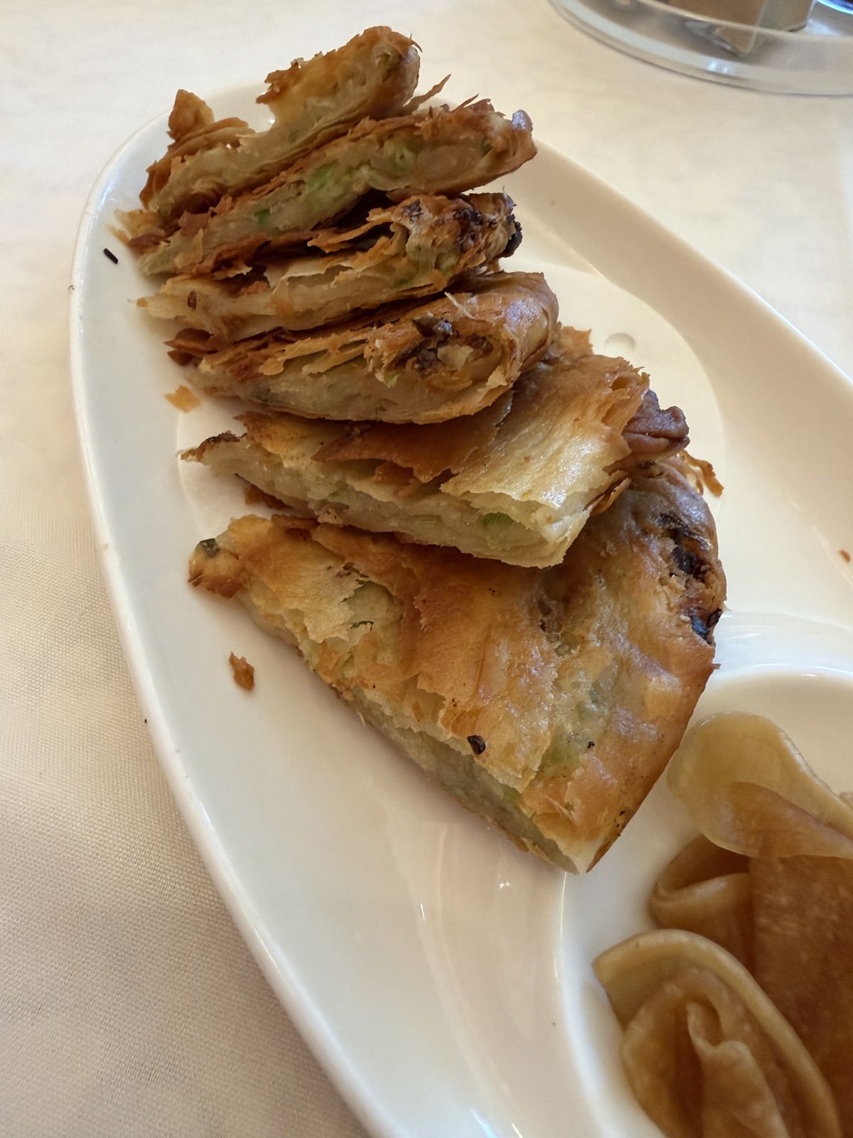 Flaky pan-fried pastry cut in wedges, with folded buns at HK Lounge Bistro