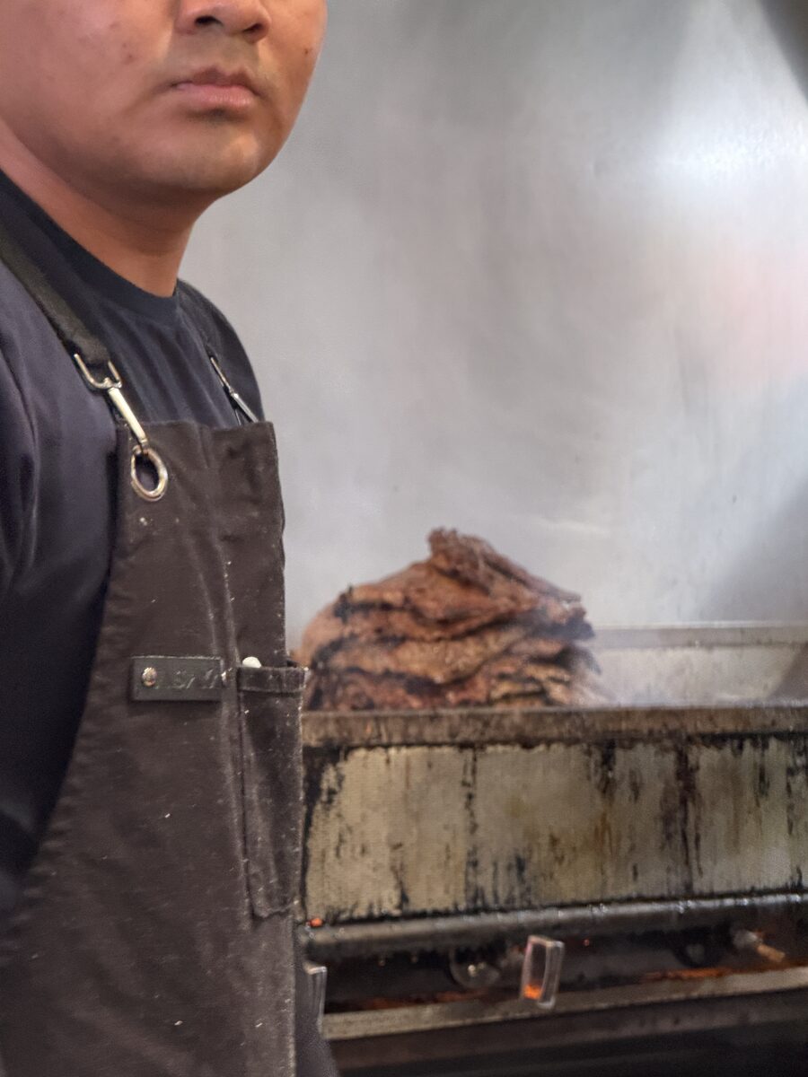 Carne asada grilling to order behind the counter at La Taqueria